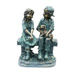 Fille et garçon assis sur un banc avec statue de chiot